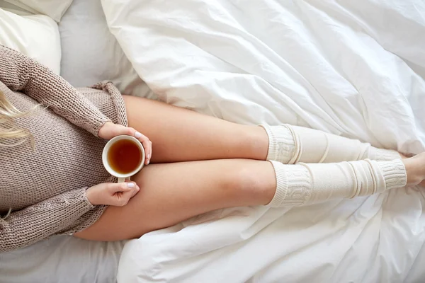 Крупним планом жінка з чашкою чаю в ліжку — стокове фото