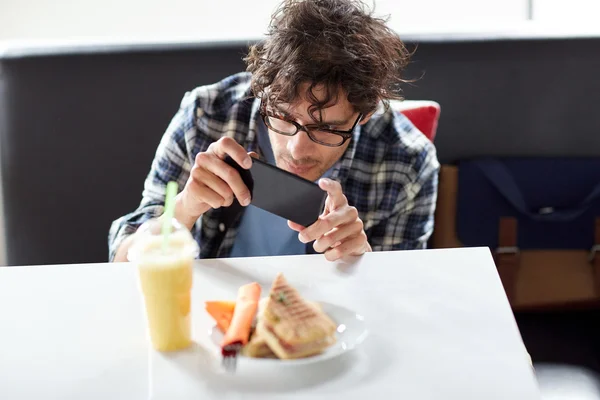 Homme avec smartphone photographier de la nourriture au café — Photo