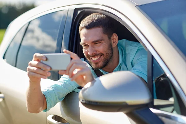 Homme souriant heureux avec smartphone conduisant en voiture — Photo