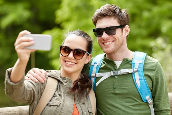 Echtpaar met rugzakken selfie te nemen door smartphone — Stockfoto