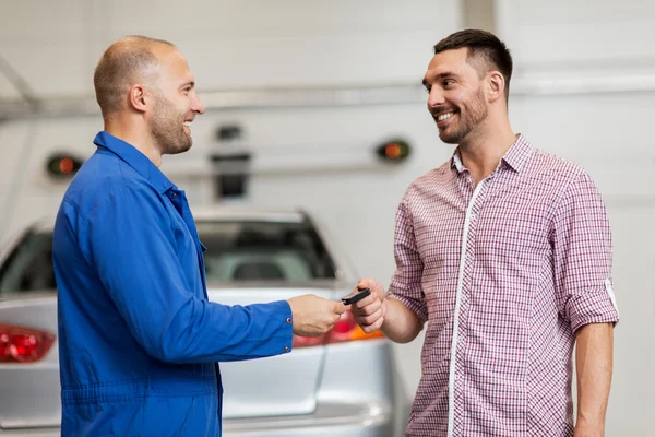 Auto mechanic giving key to man at car shop — Stock Photo, Image