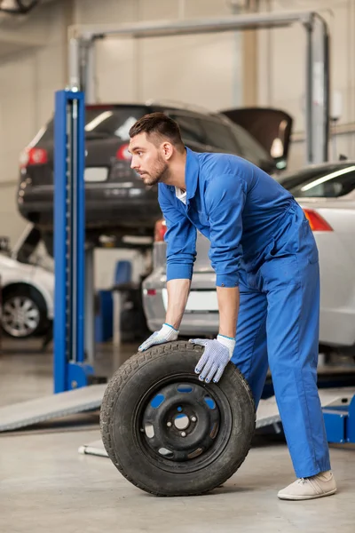 Mecánico con neumático de rueda en taller de coches —  Fotos de Stock