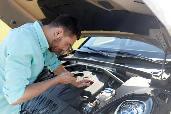 Hombre con teléfono inteligente y coche roto en el campo —  Fotos de Stock