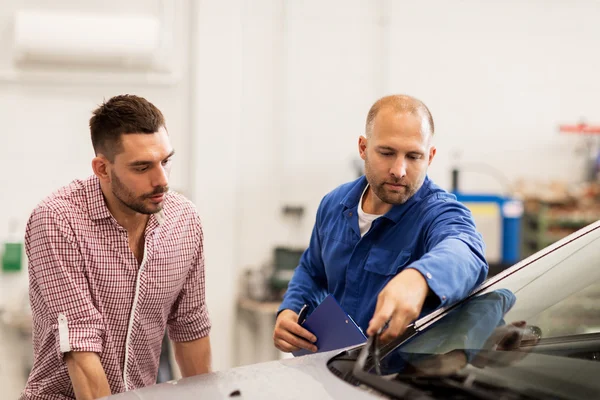 Mécanicien automobile avec presse-papiers et l'homme à l'atelier de voiture — Photo