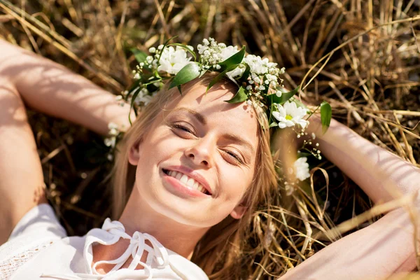 Happy woman in wreath of flowers lying on straw — Stock Photo, Image