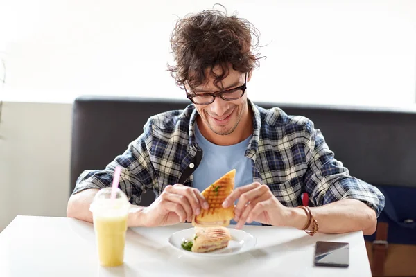 Счастливый человек ест сэндвич в кафе на обед — стоковое фото