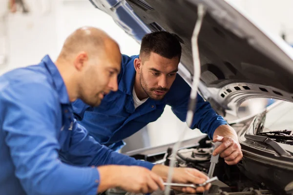 Hombres mecánicos con llave inglesa reparación de coches en el taller — Foto de Stock