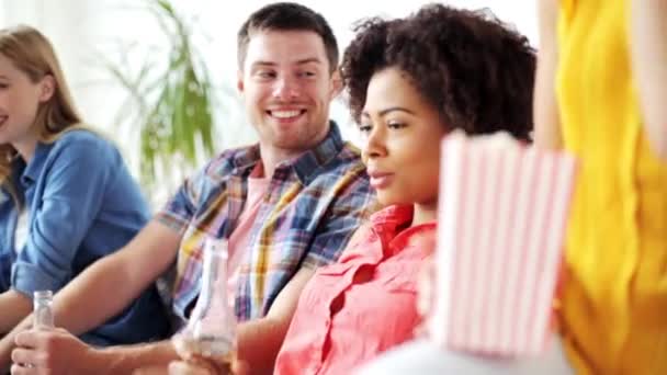 Друзья с попкорном и пивом смотрят телевизор дома — стоковое видео