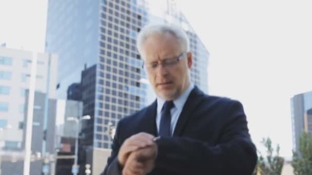 Senior businessman walking along city street — Stock Video