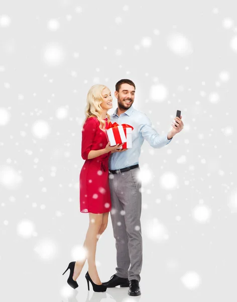 Happy couple with smartphone and christmas gifts — Stock Photo, Image