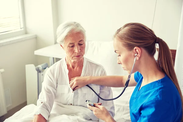 Verpleegster met stethoscoop en senior vrouw bij kliniek — Stockfoto