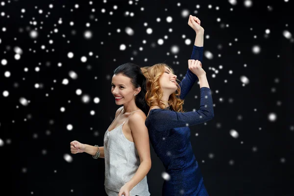 Счастливые молодые женщины танцуют над снегом — стоковое фото
