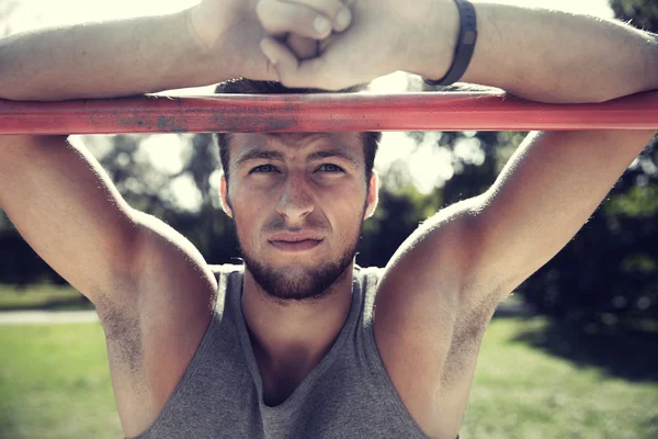 Young man exercising on horizontal bar outdoors — Stock Photo, Image