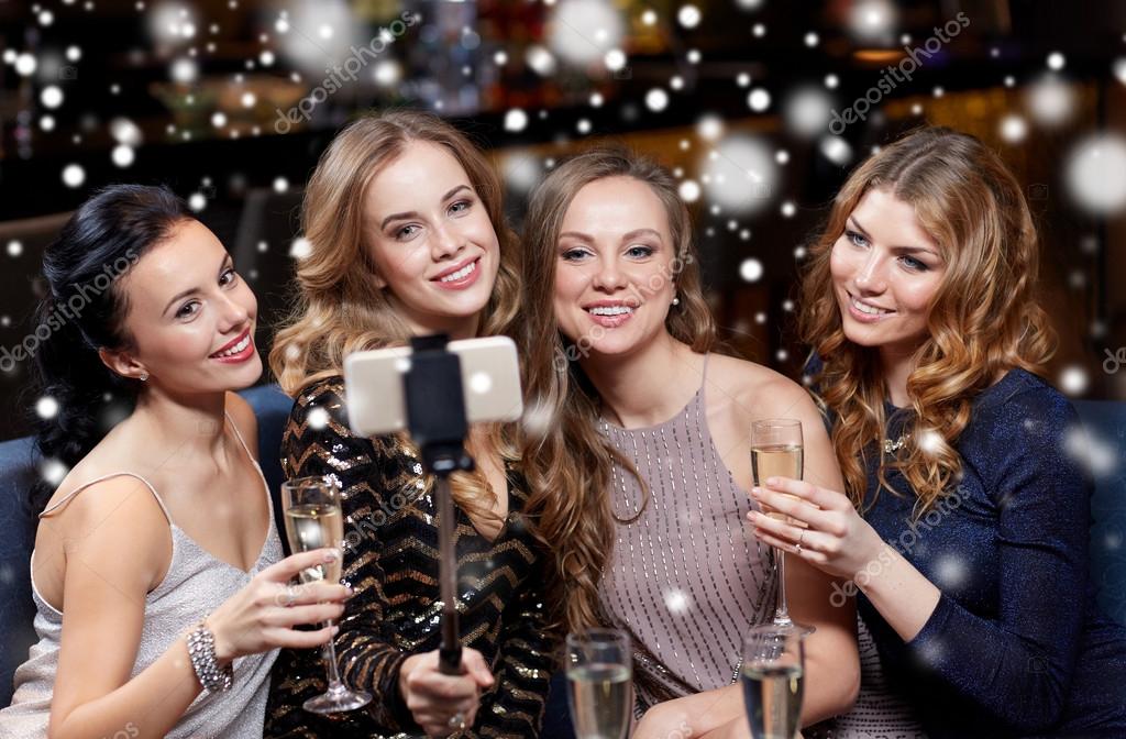 Festa, tecnologia, vida noturna e conceito de pessoas - amigos sorridentes  com smartphone tomando selfie no clube
