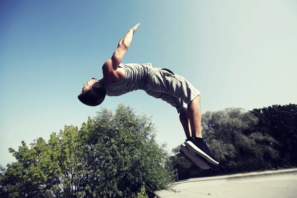 Спортивний молодий чоловік стрибає в літньому парку — стокове фото
