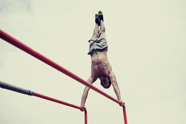 Joven ejercitándose en barras paralelas al aire libre —  Fotos de Stock