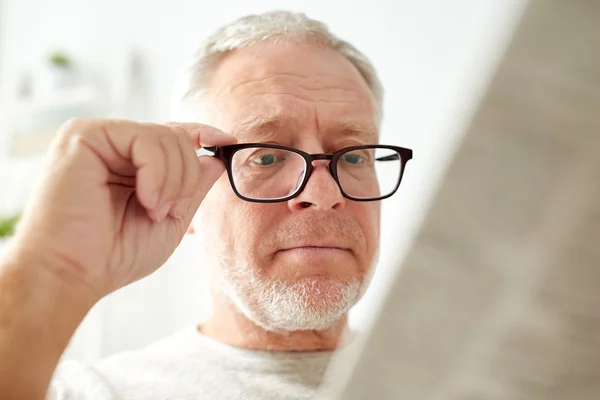 Close up of old man in glasses reading newspaper — Stock Photo, Image