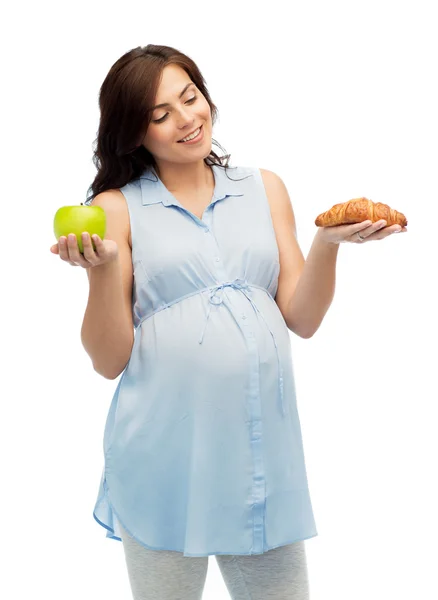 Happy pregnant woman with apple and croissant — Stock Photo, Image