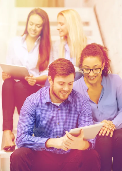 Team with tablet pc computer sitting on staircase — Stock Photo, Image