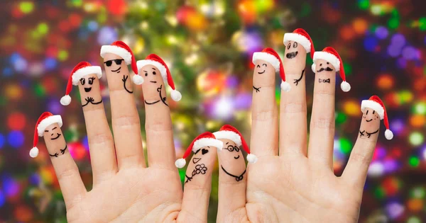 Close up of fingers with smiley in santa hats — Stock Photo, Image