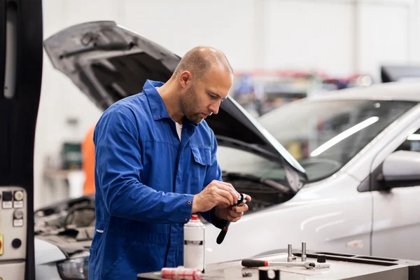 Monteur met moersleutel reparatie auto op de werkplaats — Stockfoto