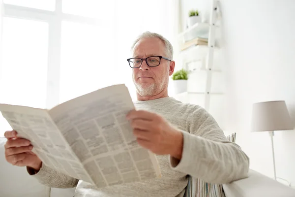 Hombre mayor en gafas leyendo el periódico en casa — Foto de Stock