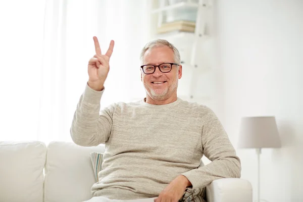 Lächelnder Senior zeigt V-Zeichen zu Hause — Stockfoto