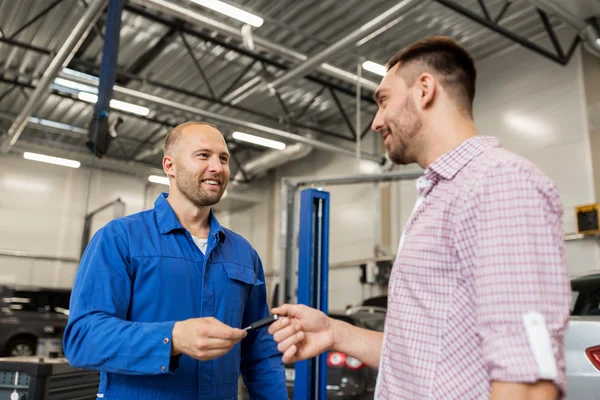 Bilmekaniker som ger nyckeln till mannen på bil shop — Stockfoto