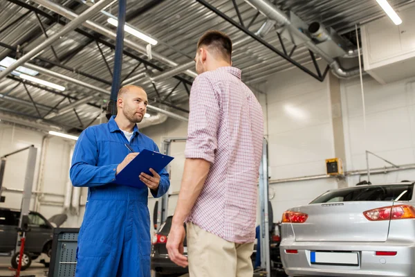 Auto mekaniker med Urklipp och man på bilverkstad — Stockfoto