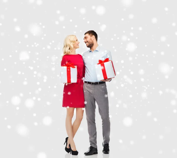 Счастливая пара с рождественскими подарочными коробками на снегу — стоковое фото