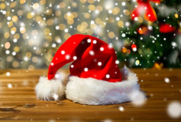 Close up of santa hat on wooden table over lights — Stock Photo, Image