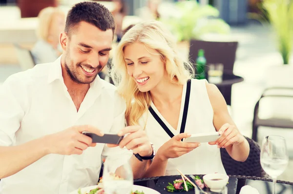 Feliz pareja con smatphone fotografiando comida — Foto de Stock