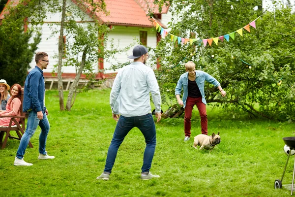 Amigos felizes brincando com o cão no jardim de verão — Fotografia de Stock