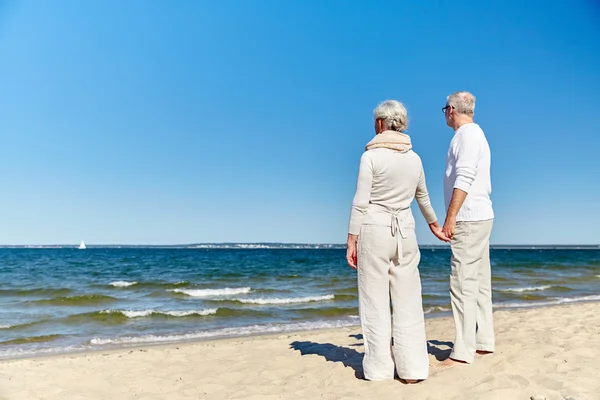 Feliz pareja de ancianos cogidos de la mano verano playa — Foto de Stock