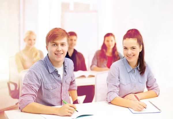 Estudiantes sonrientes con cuadernos en la escuela — Foto de Stock