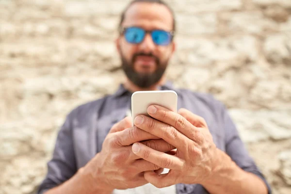 Close up of man with smartphone at stone wall — Stock Photo, Image