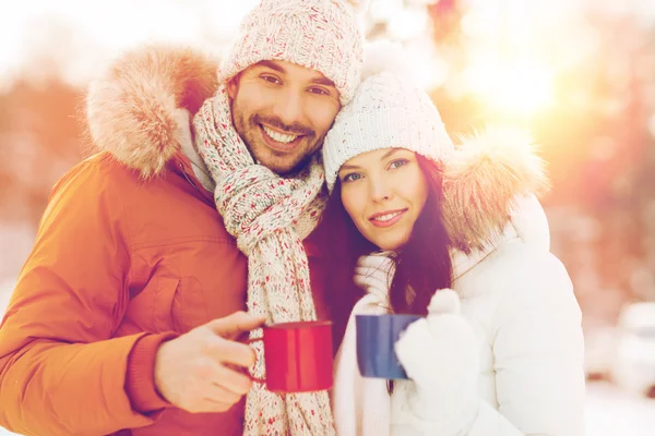 Happy couple with tea cups over winter landscape — Stock Photo, Image