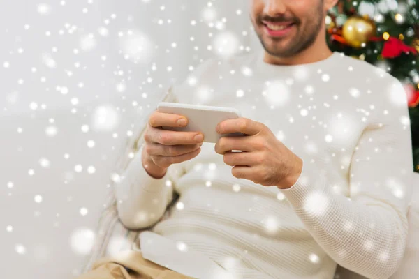 Glimlachende man met smartphone thuis voor Kerstmis — Stockfoto