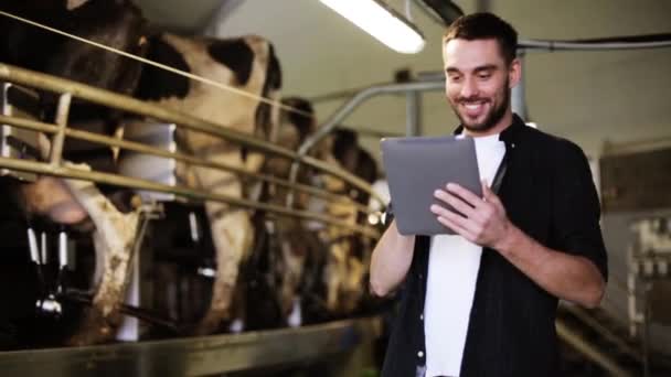 Jovem com tablet pc e vacas na fazenda de laticínios — Vídeo de Stock