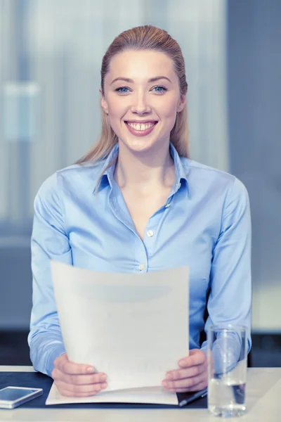 Leende kvinna anläggning papper i office — Stockfoto