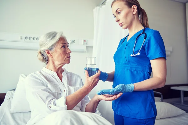 Медсестра дает лекарства пожилой женщине в больнице — стоковое фото