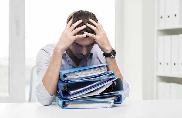 Trauriger Geschäftsmann mit Stapel Ordnern im Büro — Stockfoto