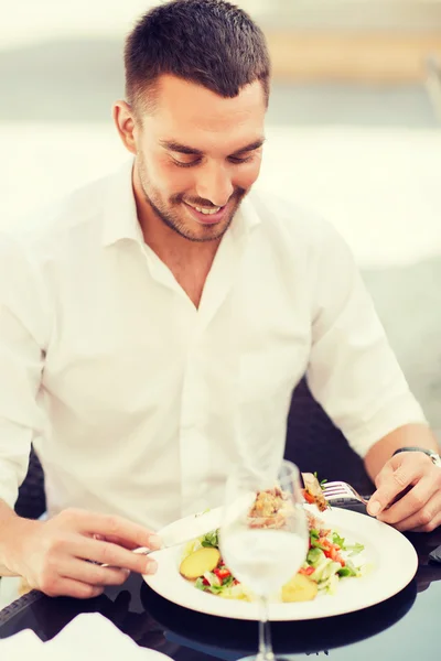 Happy man eating salad for dinner at restaurant — Stockfoto