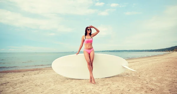 Jonge vrouw met surfboard op strand glimlachen — Stockfoto