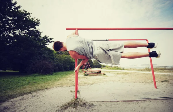 Joven ejercitándose en barras paralelas al aire libre —  Fotos de Stock