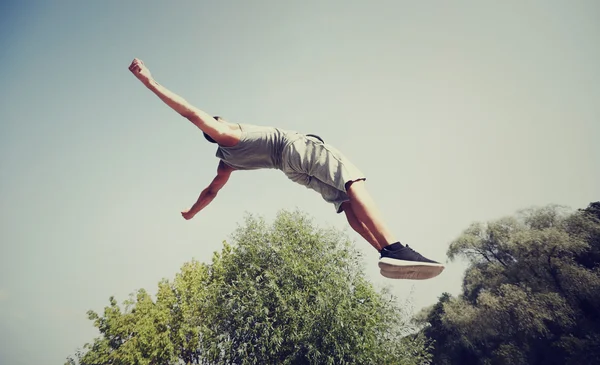 Sportovní mladý muž skákání v letním parku — Stock fotografie