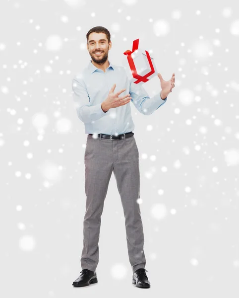 Glad ung man med presentkartong jul över snö — Stockfoto
