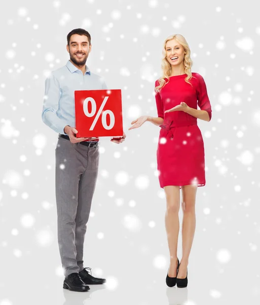 Glückliches Paar mit rotem Verkaufsschild über Schnee — Stockfoto