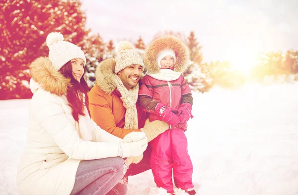 Счастливая семья с ребенком в зимней одежде на открытом воздухе — стоковое фото