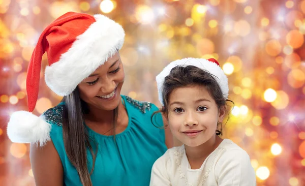 Gelukkig moeder en meisje in santa hoeden — Stockfoto